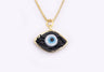 Black eye-shaped pendant with a blue and white center and gold tone border and chain against a white background.
