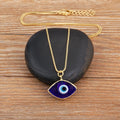 Dark blue evil eye necklace arranged over a black stone, showing the gold tone chain, pendant, clasp and extension links.