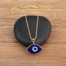 Dark blue evil eye necklace arranged over a black stone, showing the gold tone chain, pendant, clasp and extension links.