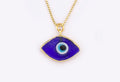 Dark blue eye-shaped pendant with a blue and white center and gold tone border and chain against a white background.