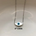 White marquise evil eye pendant with a blue center on a silver tone chain, shown with an 8 × 16 mm annotation.