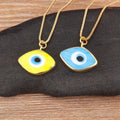 Yellow and light blue eye-shaped necklace pendants with blue and white centers and gold tone borders, displayed side by side.