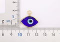 Wide view of a dark blue eye-shaped pendant beside two rulers marked in centimeters.