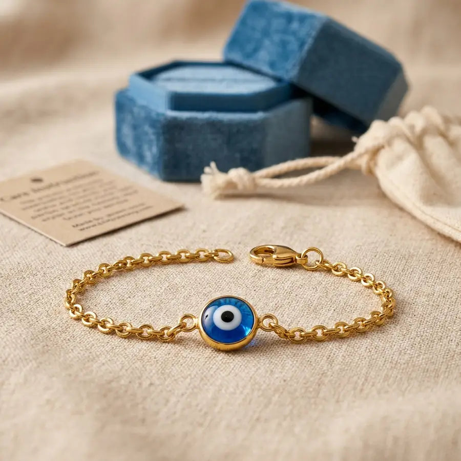 A close-up of an evil eye bracelet shows its clasp and surface finish in front, with a box and care packaging blurred behind