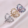 Silver tone, gold tone and rainbow evil eye rings arranged diagonally on pale fabric, each with a beaded oval frame.