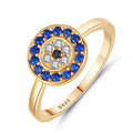 Angled view of a gold tone evil eye ring with a blue halo and clear accents around a black center