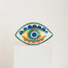 Evil eye statue with a yellow inner eye, blue upper petals, pink lower petals and a turquoise dotted border.