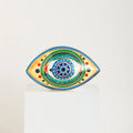 Almond-shaped evil eye statue with a blue starburst center, green rings and yellow side panels.