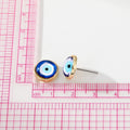 Blue evil eye stud earring beside a centimeter ruler showing its diameter