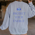 Gray sweatshirt worn from the back, with a blue evil eye above "PROTECT YOUR ENERGY" lettering