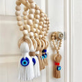 White and tan evil eye tassel hangings with pale beaded loops displayed on a door