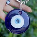 Close view of a round blue eye pendant with white and light blue rings and a short silver tone chain
