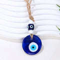 Deep blue round evil eye pendant with a blue cube bead, two white beads and knotted tan cord