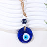 Deep blue round evil eye pendant with a blue cube bead, two white beads and knotted tan cord