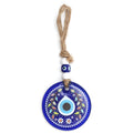 Blue evil eye wall hanging with colorful leaves, small flowers and a white dotted border around a teardrop eye
