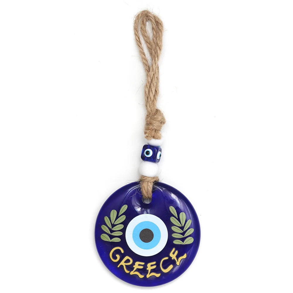 Blue evil eye wall hanging with green leafy branches, GREECE lettering and a beaded rope loop
