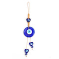 Round blue evil eye hanging with a blue heart above and two blue heart drops on uneven tan cords