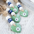 Green heart evil eye pendants with white eye surrounds, dark blue eye beads and tan rope
