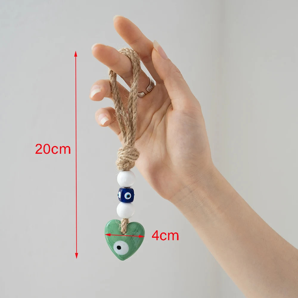 Green heart evil eye hanging held by its tan rope loop, with red arrows labeled 20 cm and 4 cm