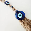 Angled view of blue eye discs, a tan cord-wrapped center and loose tassel fringe