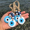 White and turquoise evil eye hangings with blue cube beads resting on a hand