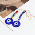 Two round blue evil eye pendants with colorful disc beads and a row of six blue eye beads on tan cord