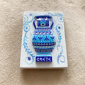 White rectangular magnet with a raised blue and turquoise two-handled vase, patterned bands and CRETE lettering.