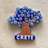 Tree-shaped magnet with an orange trunk, blue canopy of eye motifs and white CRETE lettering on a blue base.