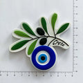 Olive branch magnet with green leaves, black olives, a blue and white eye and Crete lettering beside ruler markings.