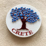 Round white magnet with a dark red tree, a canopy of raised blue eye motifs and CRETE lettering.