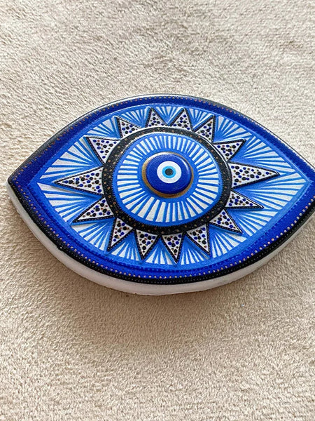 Blue and white almond-shaped eye magnet with radiating lines and triangular points, shown at an angle.