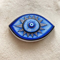 Blue and white almond-shaped eye magnet with radiating lines and triangular points, shown at an angle.