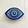 Blue and white almond-shaped eye magnet with radiating lines and triangular points beside ruler markings.