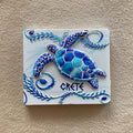 Blue and turquoise turtle on a white rectangular magnet with curling leafy borders and CRETE lettering.