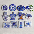 Twelve predominantly blue and white magnets arranged in three rows, including eyes, trees, turtles, a hand, an olive branch, a vase and a fish.