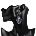 Blue Hamsa drop earring displayed on a black mannequin head, showing the diamond-shaped top above the hanging hand.