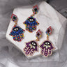 Blue and Purple Hamsa earring pairs arranged together on a white slab, showing their different accent colors.