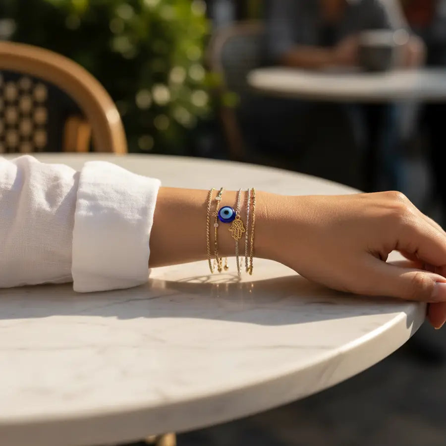Woman's wrist wearing delicate protective bracelets with an Evil Eye bead and a Hamsa charm
