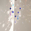 Close view of five clear pointed drops suspended beneath round blue eye beads on silver tone chains.