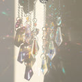 Close view of clear faceted accents and five elongated pointed drops on silver tone chains, with the center drop lowest.