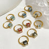 Gold tone hoop earrings with evil eye cube beads in five colors, arranged in matching pairs on a white surface