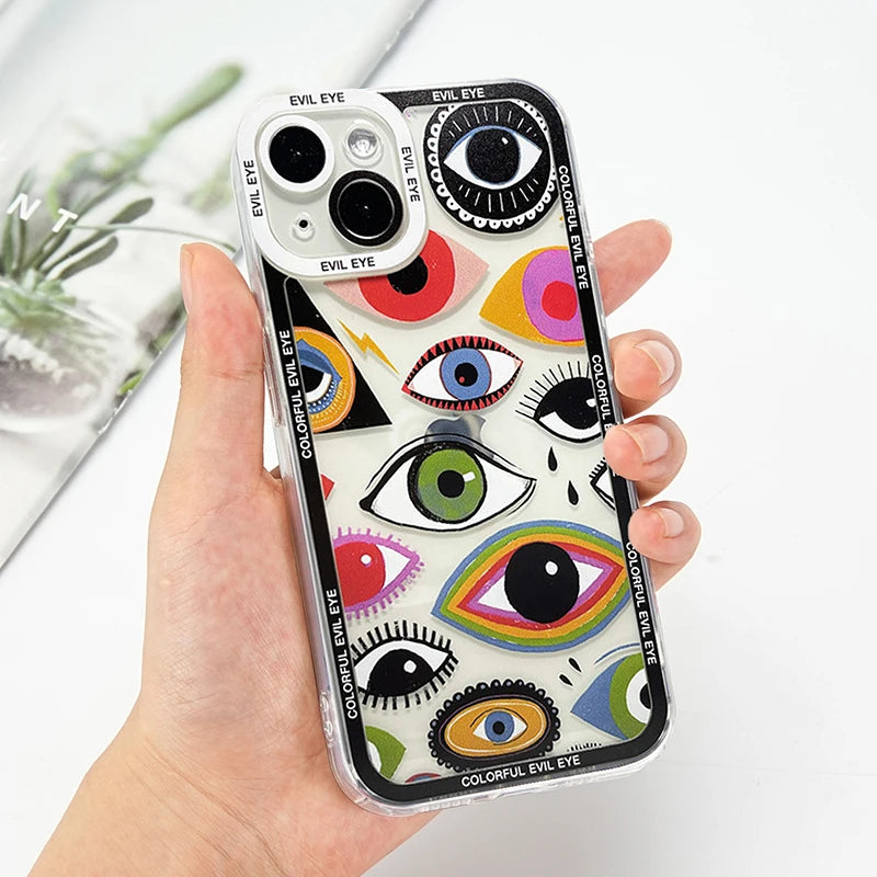 Clear iPhone case with a multicolored eye collage and black lettered border, held in a hand