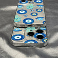 Two overlapping phones in blue eye and turquoise Hamsa cases, showing the bottom port opening and camera cutouts.