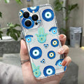 Clear phone case with blue eye circles, turquoise Hamsa hands and small hearts, shown on a light-colored phone.