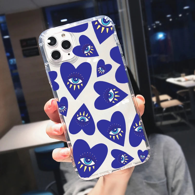 Hand holding an iPhone case with blue hearts, turquoise and white eyes, yellow rays and clear edges