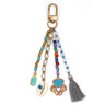 Multicolored beaded keychain with bottle, heart and feet charms, a shell-shaped eye charm and grey tassel