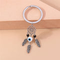 Silver tone keychain with an open flower circle, a central white and blue eye bead, two black beads and three feathers.