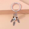 Silver tone keychain with an open flower circle, a central white and blue eye bead, two black beads and three feathers.