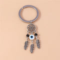 White and blue center eye bead beneath an open flower circle, flanked by black beads and three silver tone feather charms.