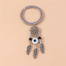 White and blue center eye bead beneath an open flower circle, flanked by black beads and three silver tone feather charms.
